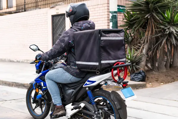 Entregador com mochila de delivery usando moto com CNH ativa
