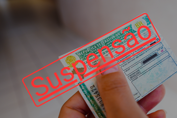CNH suspensa com carimbo vermelho de “Suspensa” e documentos ao fundo