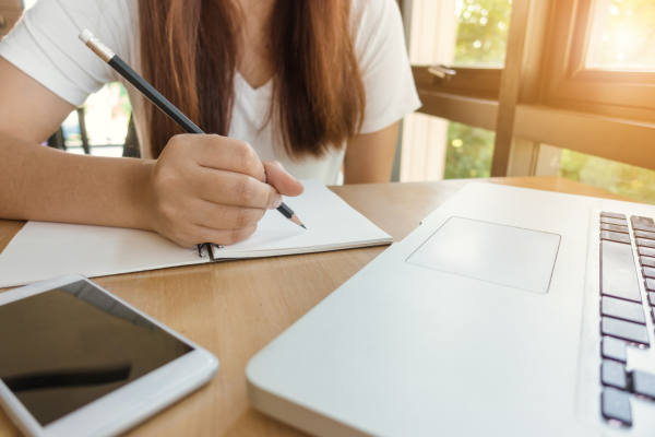 Candidato estudando para a prova do Detran com apostila do curso de formação em uma mesa com caderno e celular